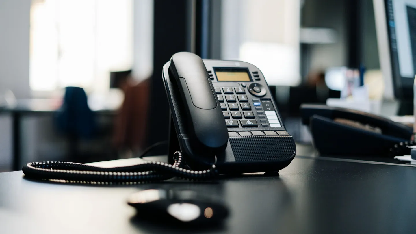 black ip desk phone on black wooden table