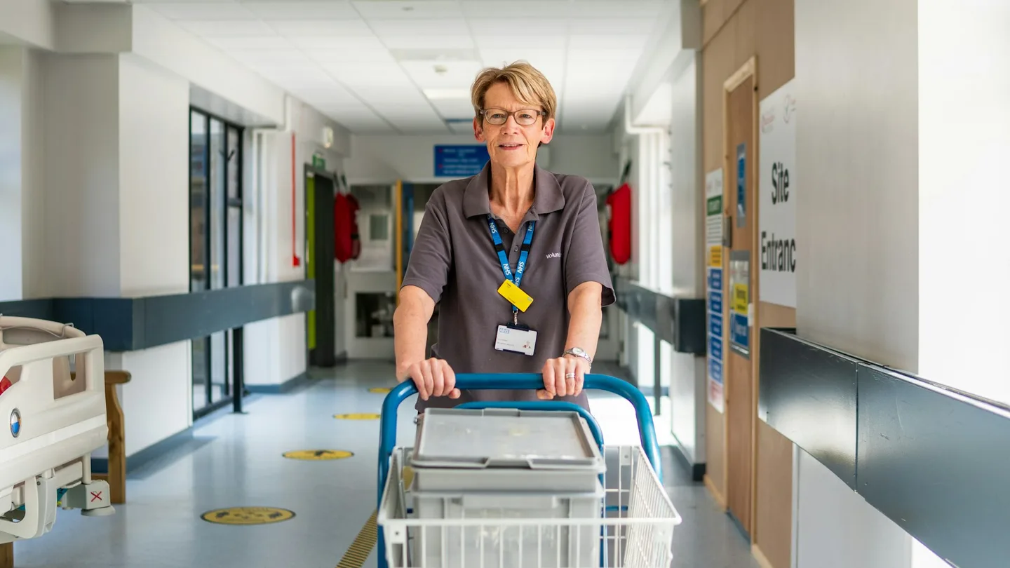 A member of hospital staff with a trolley in a corridor